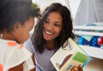 Woman smiling at boy, who is reading a book Woman smiling at boy, who is reading a book