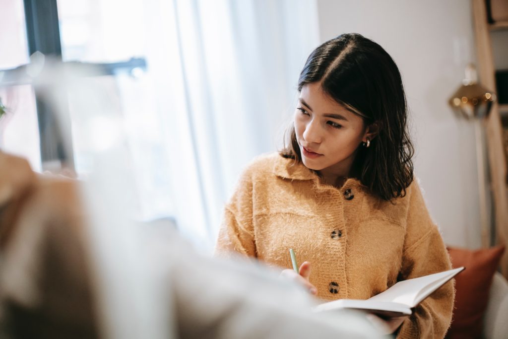 Image of woman sat down looking to her right with a book in her hand