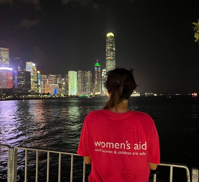 A woman looking out to the Thames in a Women's Aid T-Shirt.