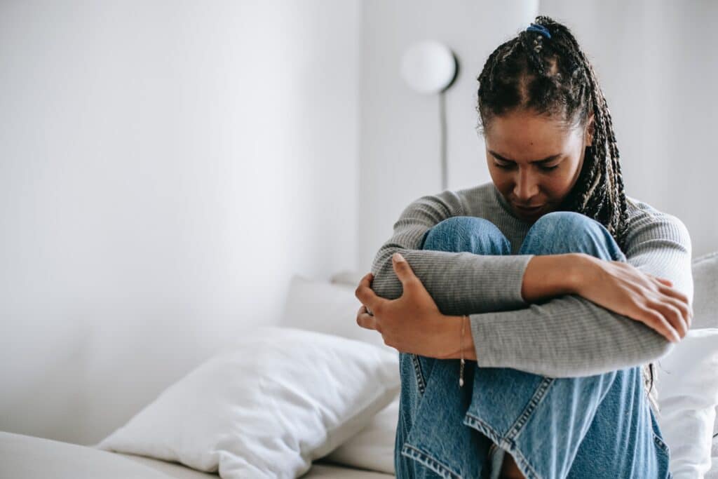 Woman sitting on a bed with her head down